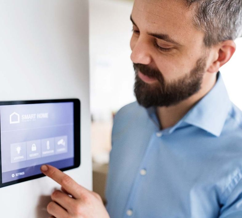 Ein Mann der auf einem Tablet an der Wand etwas einstellt