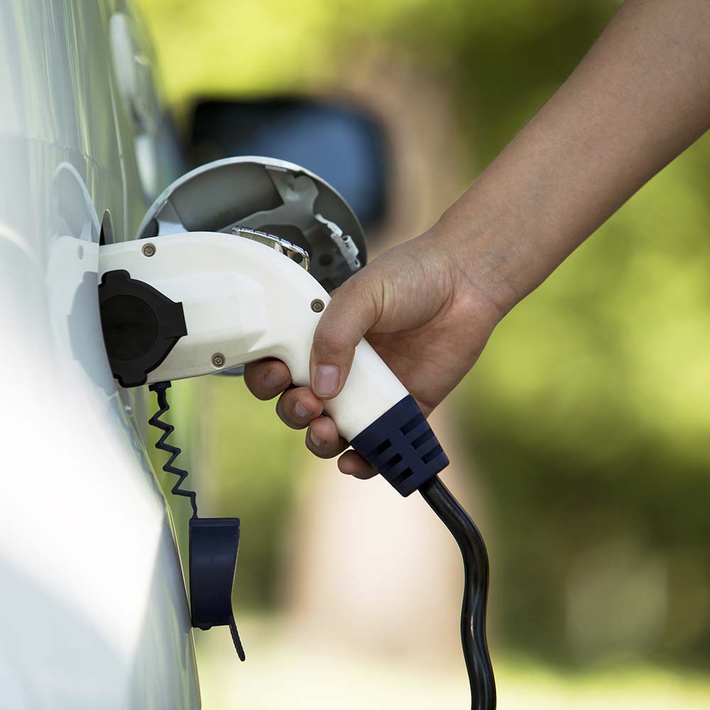 Eine Person, die gerade sein Auto an einer Ladestation lädt